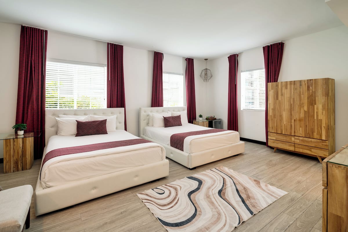 Une chambre avec deux lits, une armoire en bois et une petite table de chevet agrémentée d’une plante.