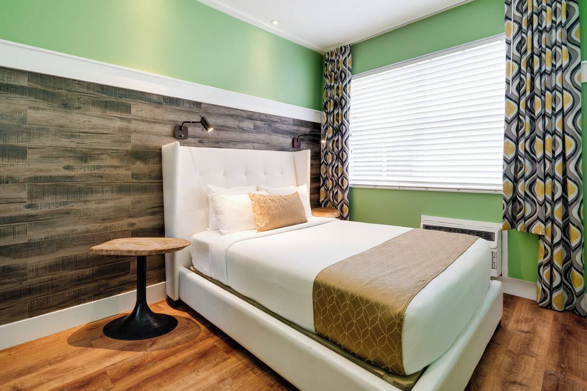 Une chambre à coucher avec un grand lit, une petite table ronde et un rideau à motifs.
