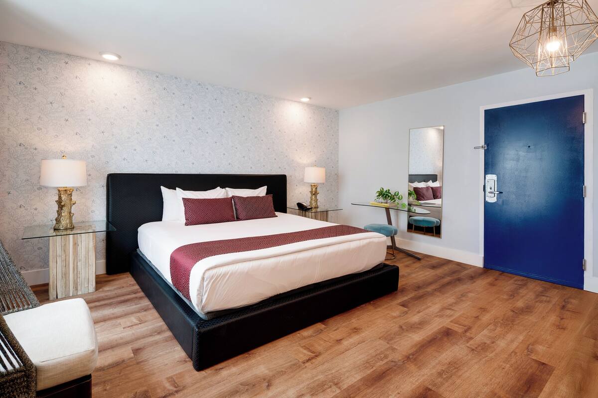 Une chambre moderne avec un grand lit, des tables de chevet, un bureau et une porte bleue.