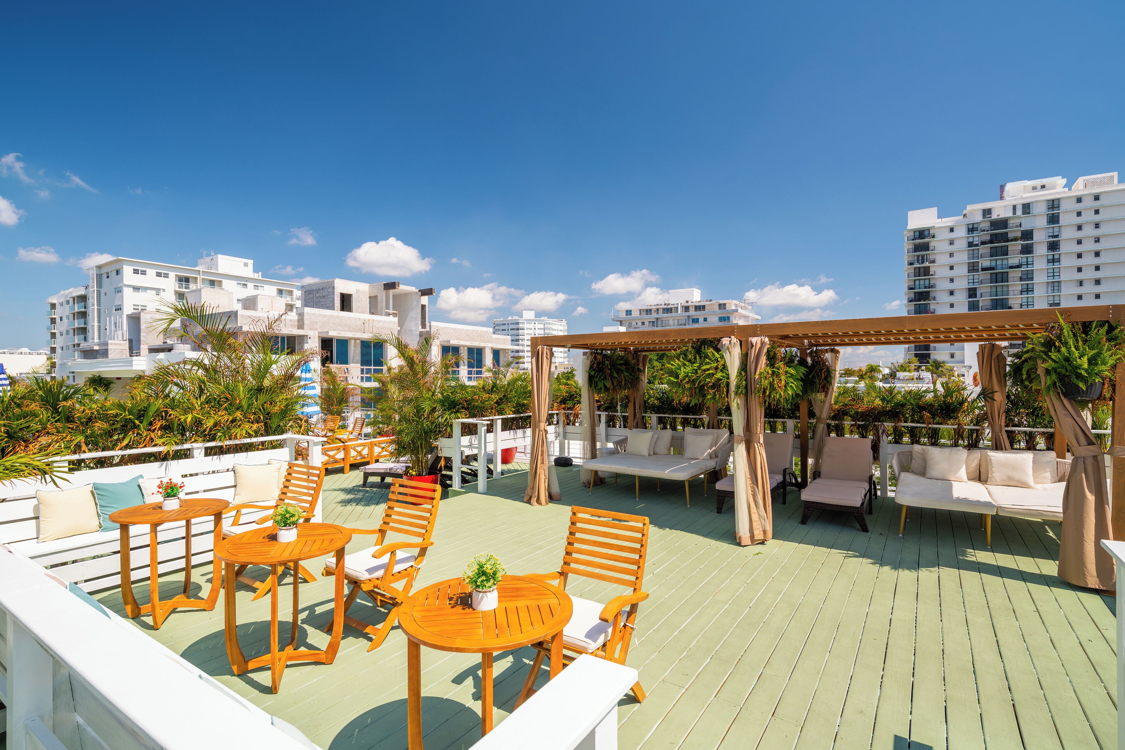 Une terrasse sur le toit, aménagée avec des espaces de détente en plein air, comprenant des tables et des chaises, entourée de verdure et offrant une vue sur le paysage urbain.