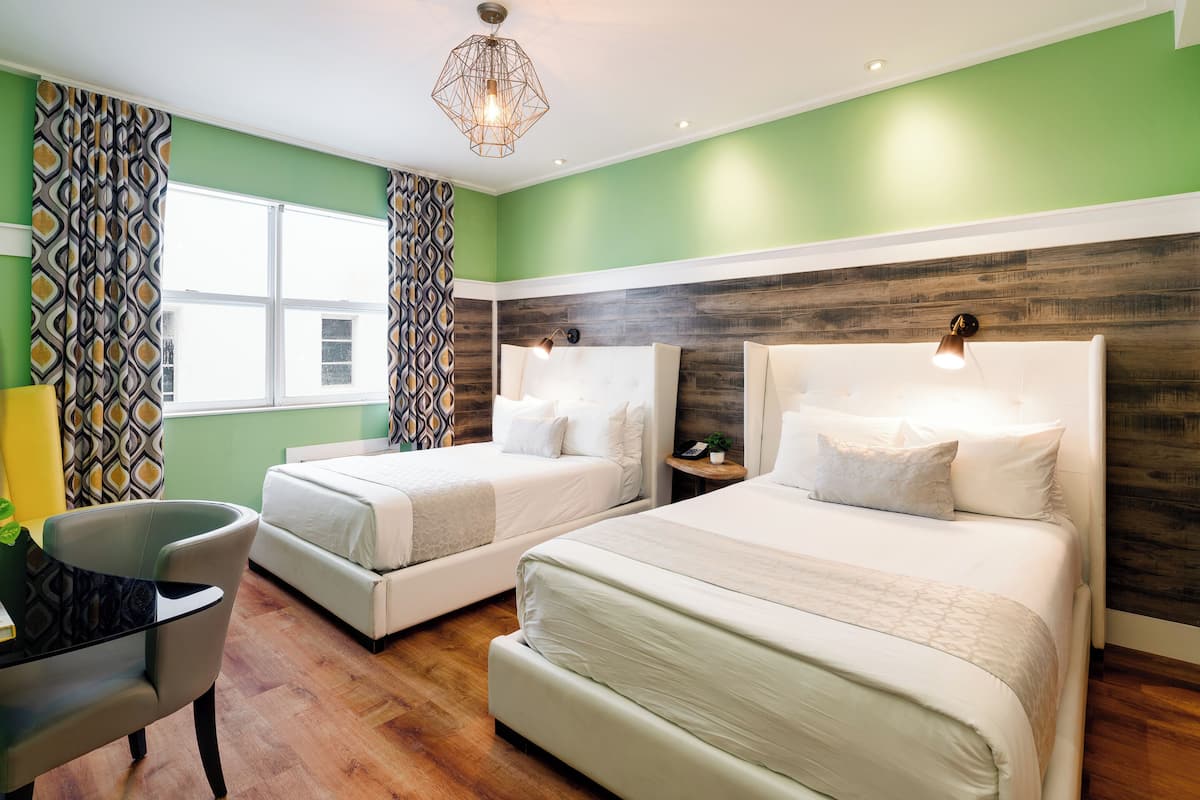 Une chambre d’hôtel avec deux lits, un bureau et une chaise.