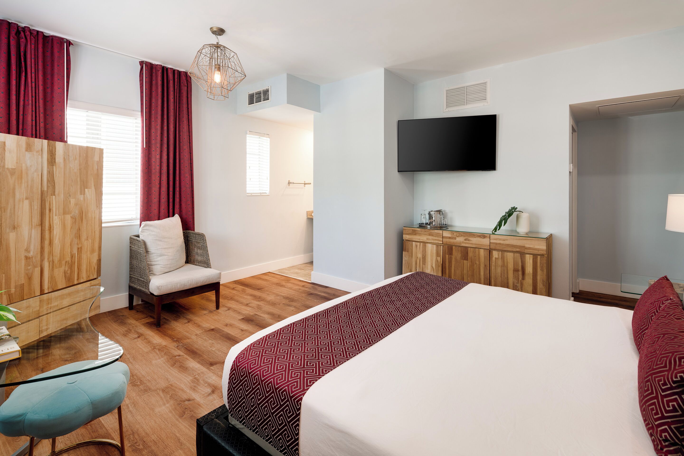 A hotel room with a bed, a chair, a desk, a TV, and a wardrobe.