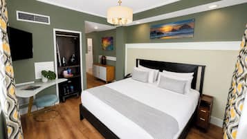 Ein Hotelzimmer mit einem Bett, einem Schreibtisch, einem Sessel, einem Fernseher, einem Gemälde und einem Fenster.