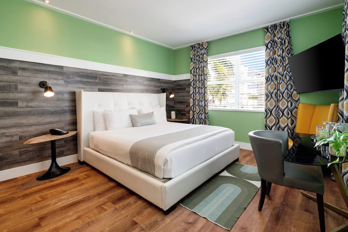 Une chambre à coucher moderne avec un lit, une table de chevet et un téléviseur fixé au mur.