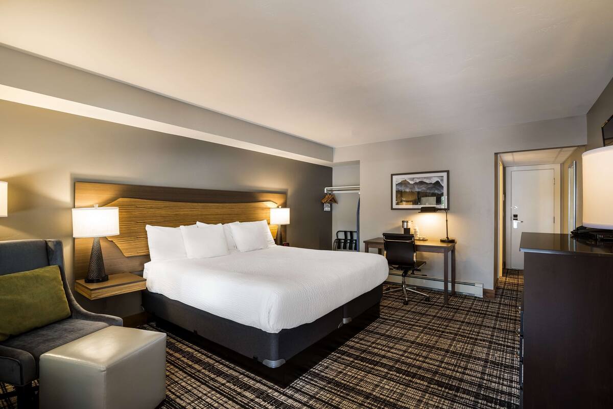 A hotel room with a large bed, a desk, a chair, and a small couch.