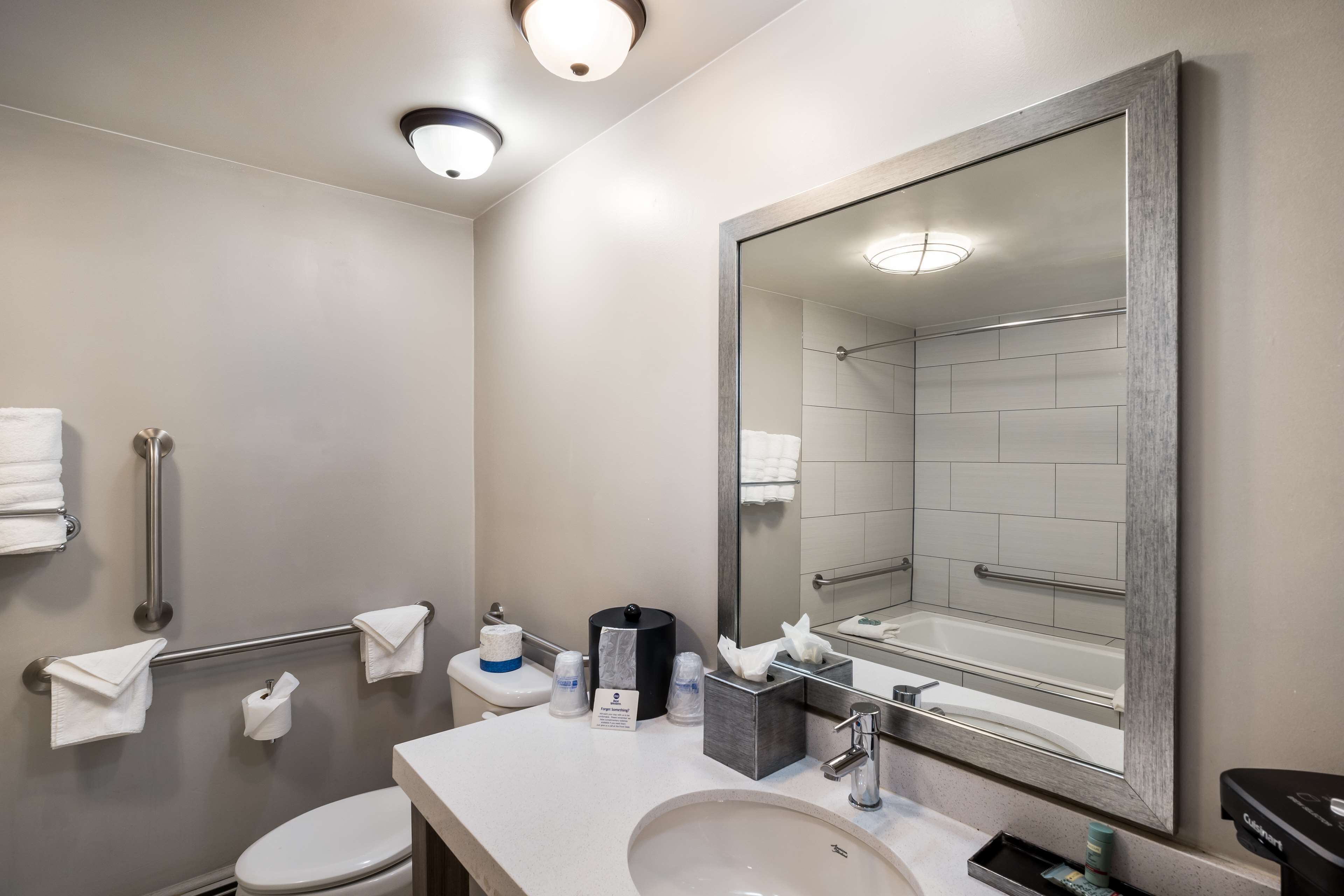 Un baño moderno con un espejo grande, un lavabo, un inodoro y una zona de ducha.
