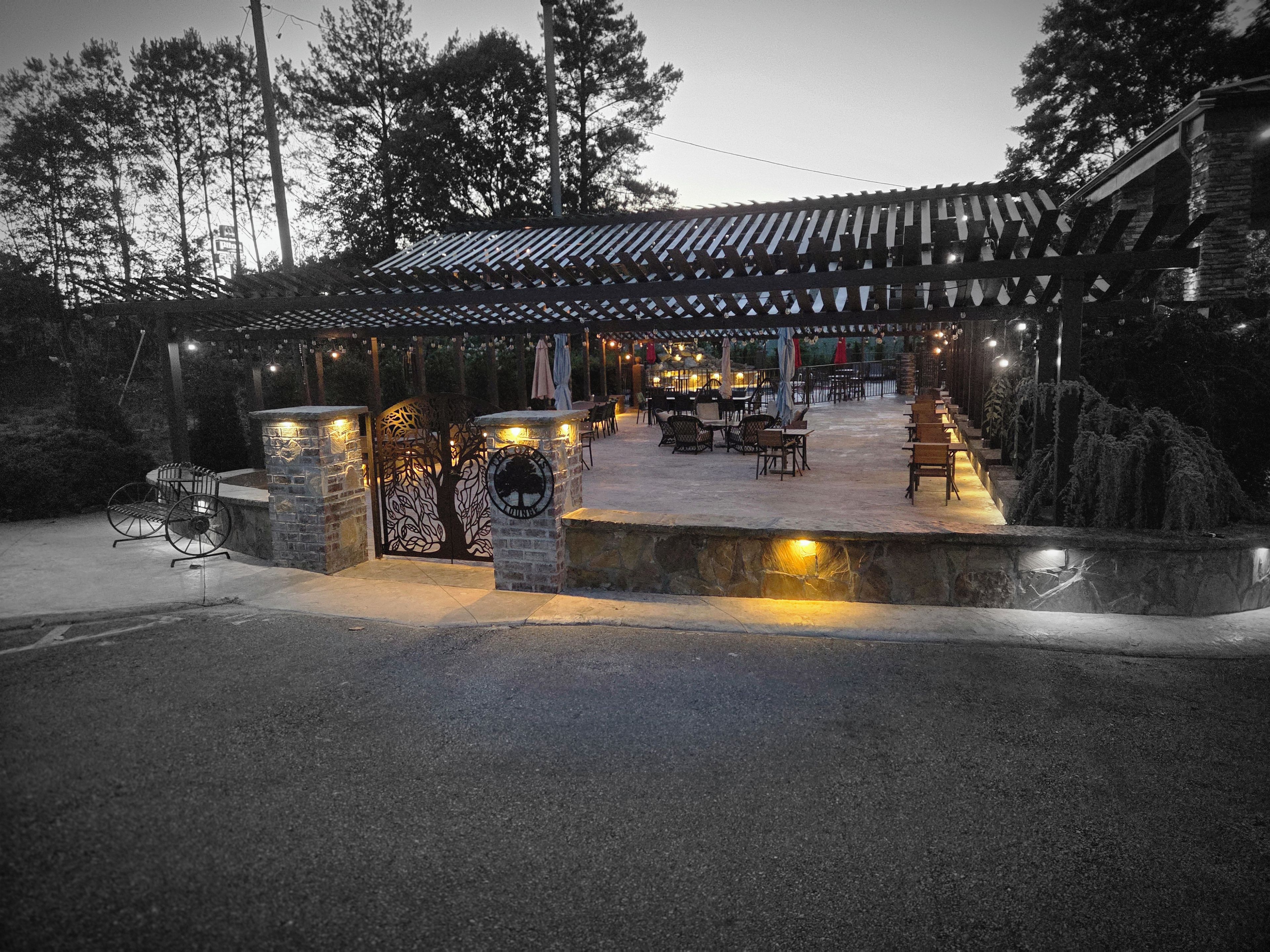 Un patio al aire libre con paredes de piedra, asientos y una estructura de pérgola.