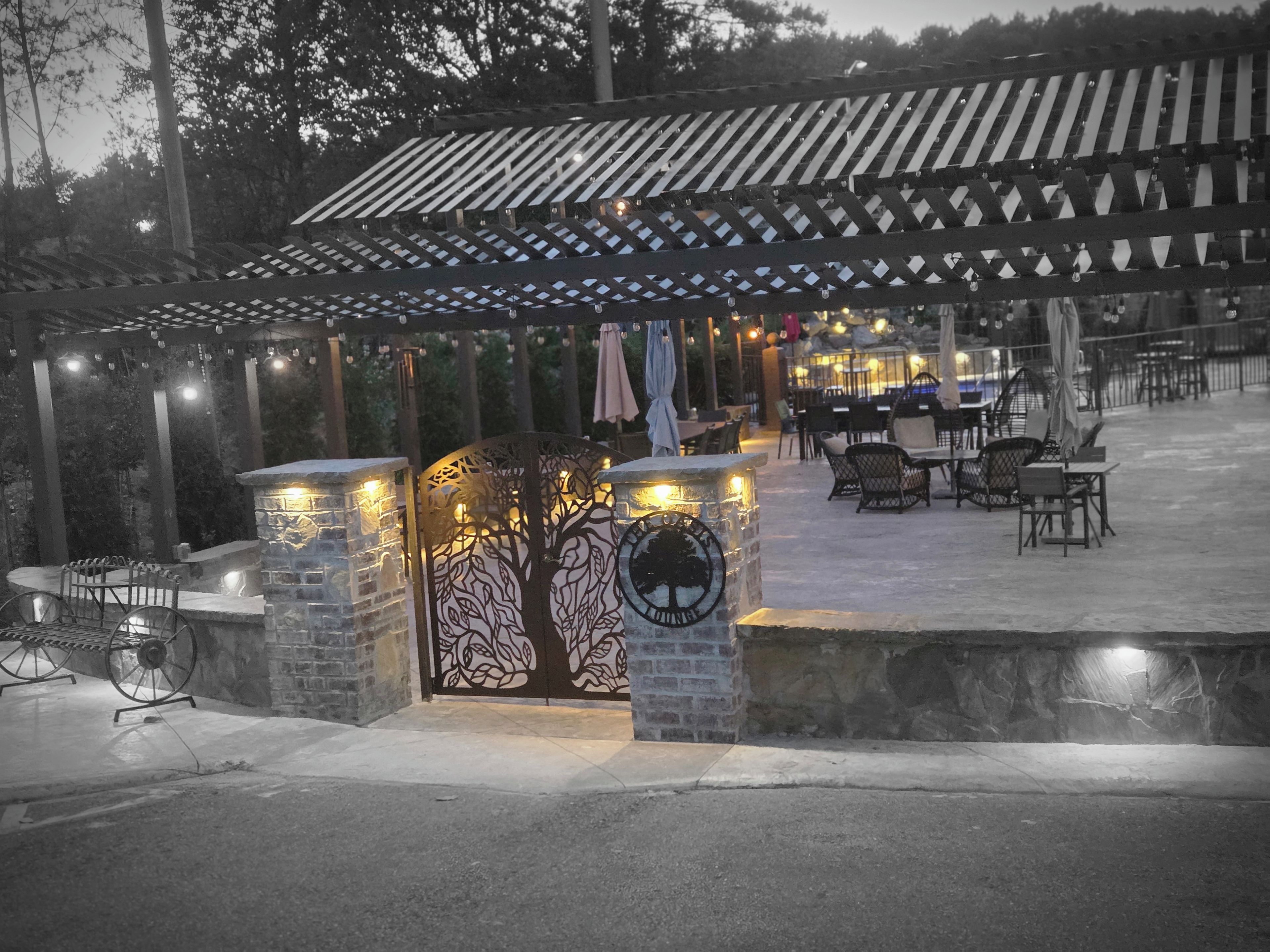 Un espace extérieur aménagé en terrasse, avec une pergola, des piliers en pierre et un coin salon.