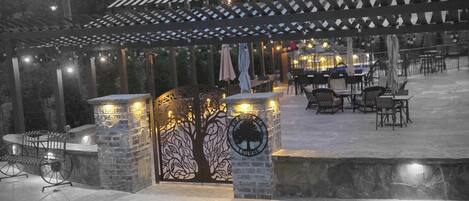 Un espace extérieur aménagé en terrasse, avec une pergola, des piliers en pierre et un coin salon.