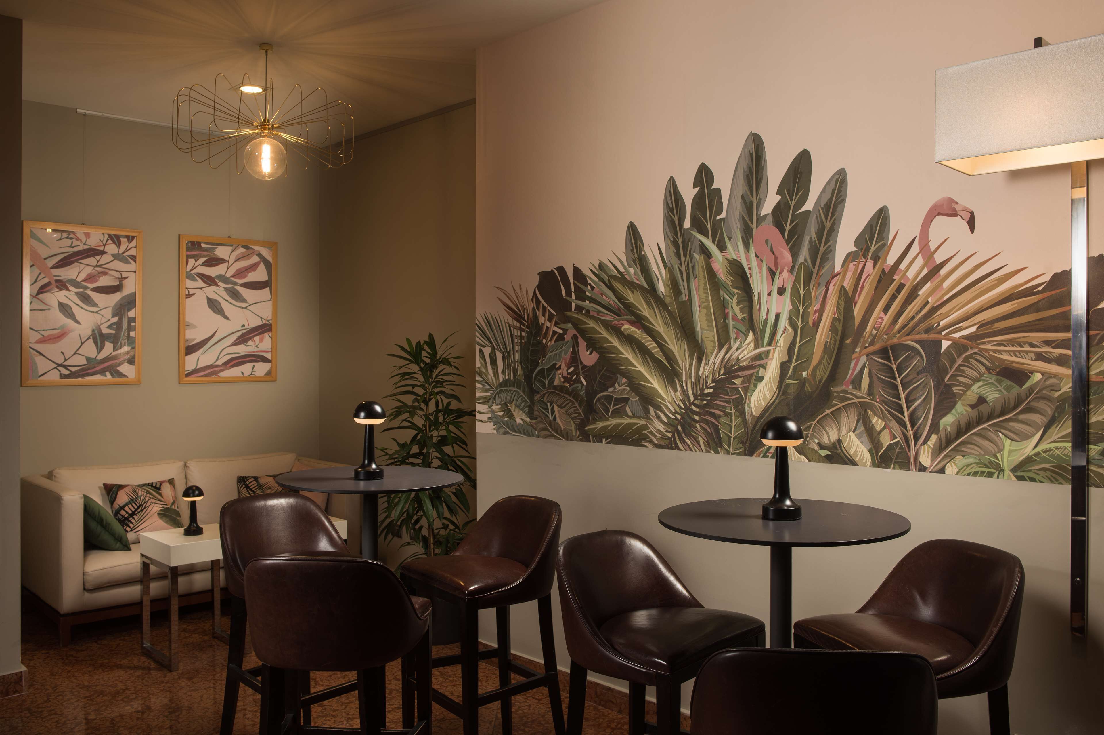 A modern lounge area with leather chairs, a round table, and a large tropical mural on the wall.