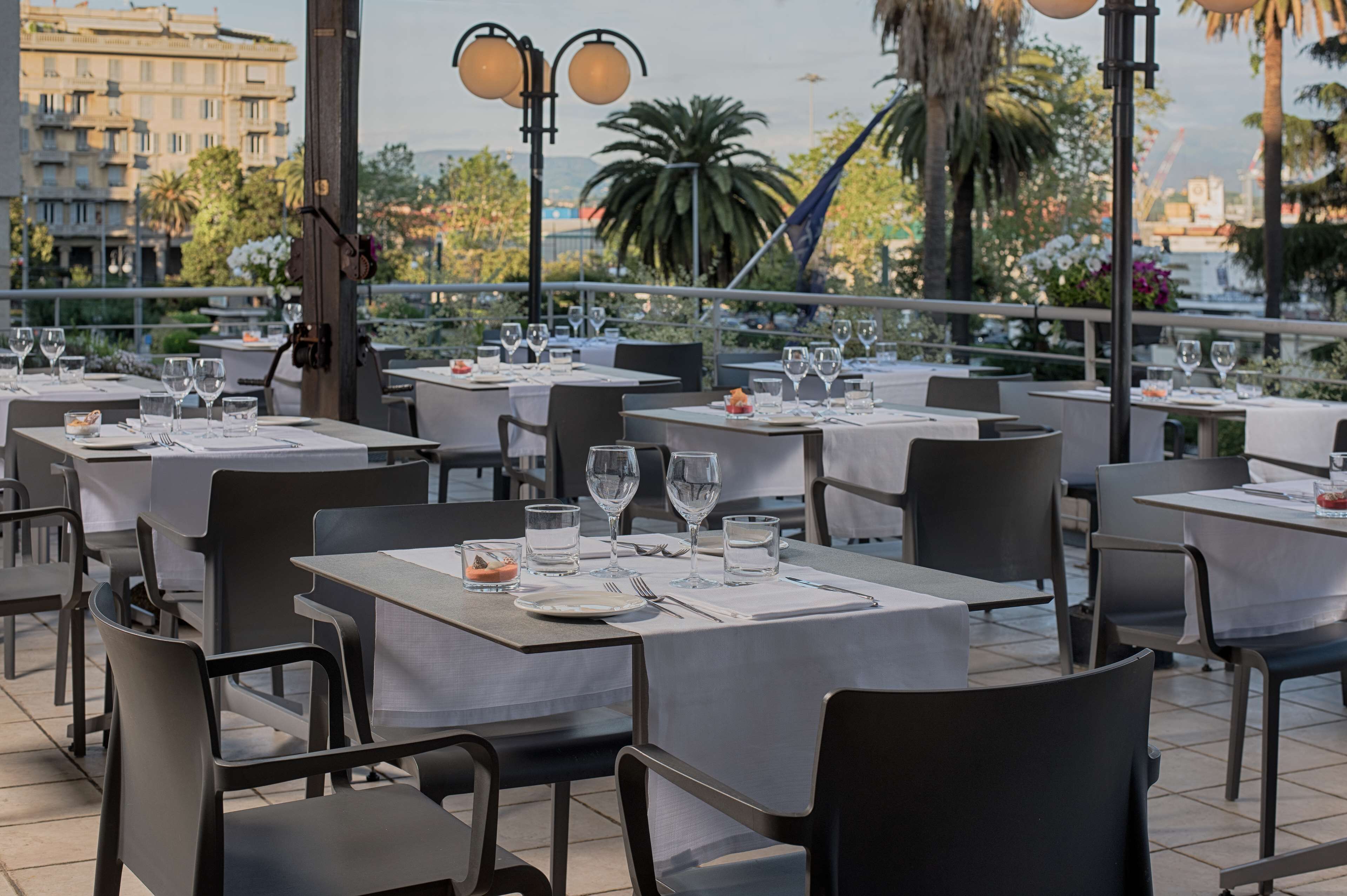 Ein Restaurant auf dem Dach mit mehreren Tischen, Außenbereich und Blick auf die Stadt.