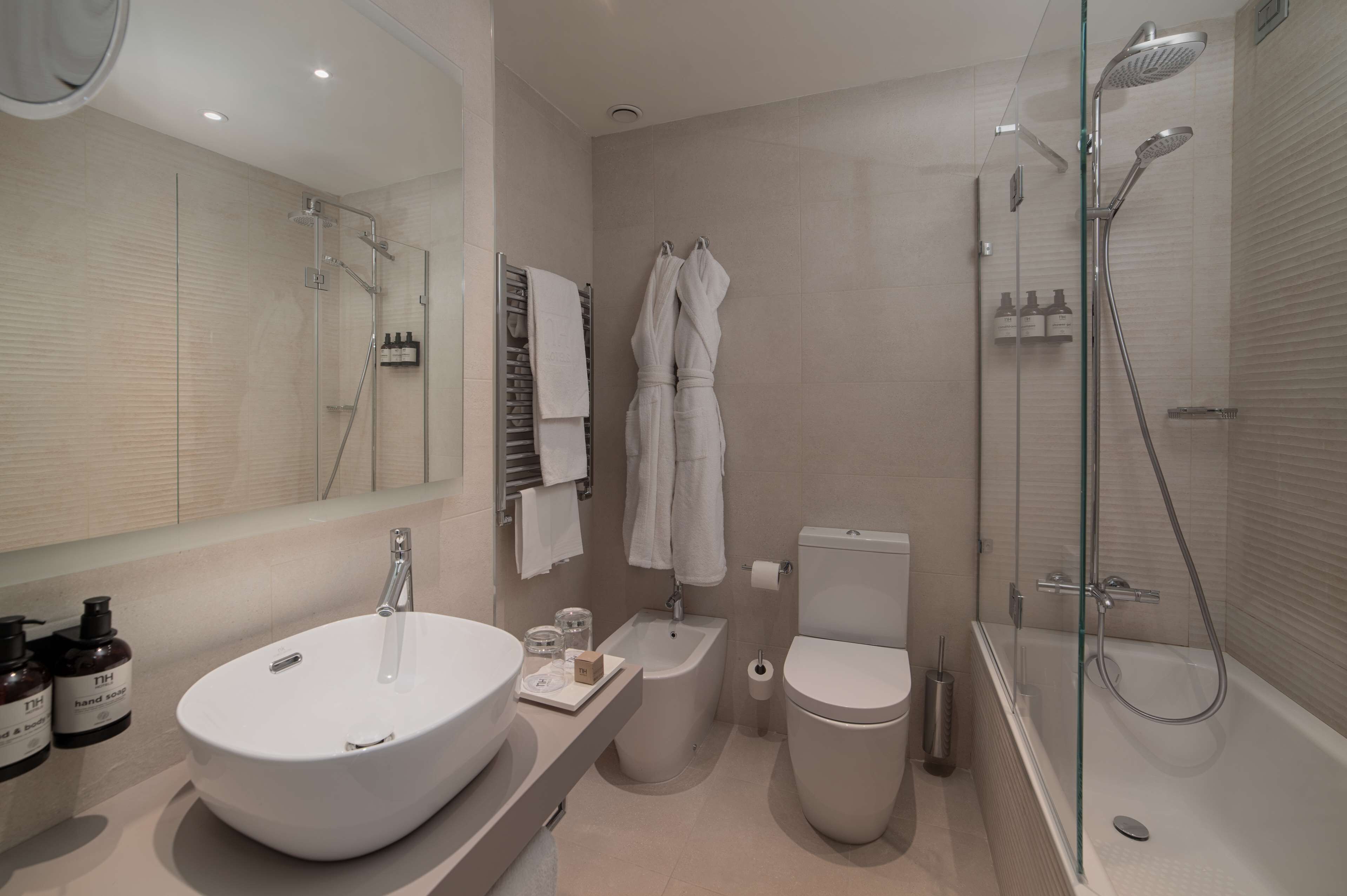Ein modernes Badezimmer mit einem großen weißen Waschbecken, einer gläsernen Dusche und einer Toilette.