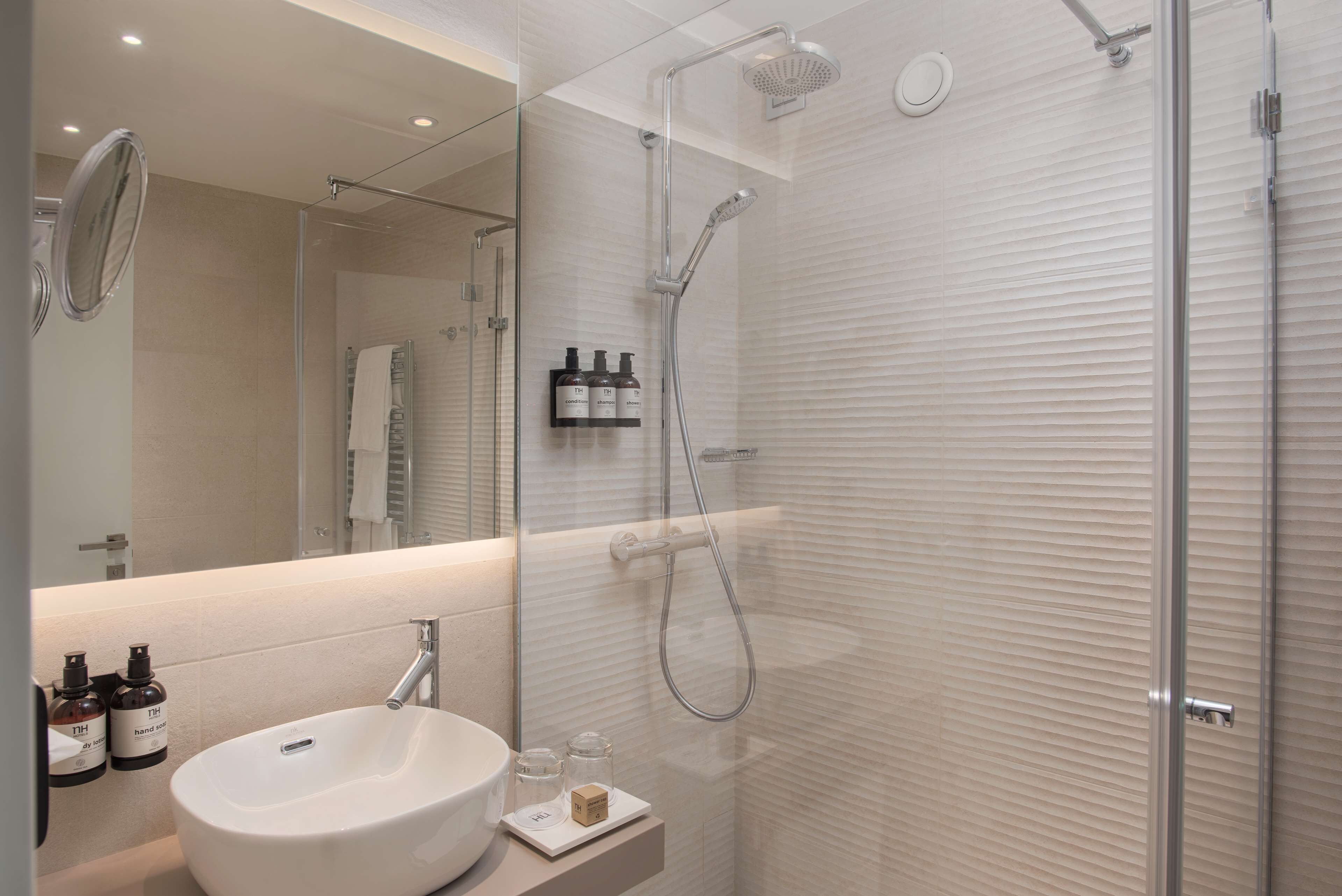 A modern bathroom with a glass-enclosed shower, a white sink, and a mirror.