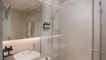 A modern bathroom with a glass-enclosed shower, a white sink, and a mirror.