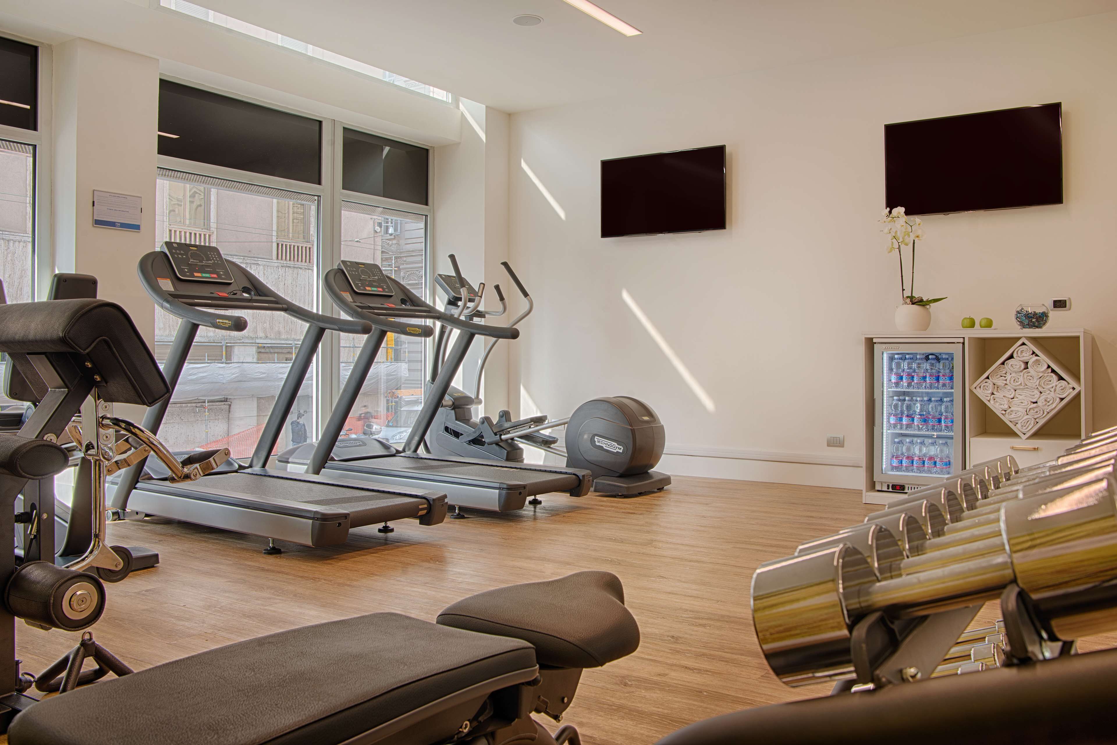 Une salle de sport équipée de tapis de course, de vélos elliptiques et de bancs de musculation.