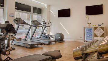 Une salle de sport équipée de tapis de course, de vélos elliptiques et de bancs de musculation.