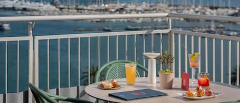 Un balcón con una mesa para dos, con vistas a un puerto deportivo con barcos.