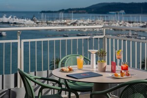 Un balcón con una mesa para dos, con vistas a un puerto deportivo con barcos.