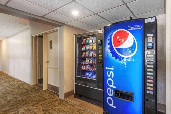 A hallway with a Pepsi vending machine and a room door.