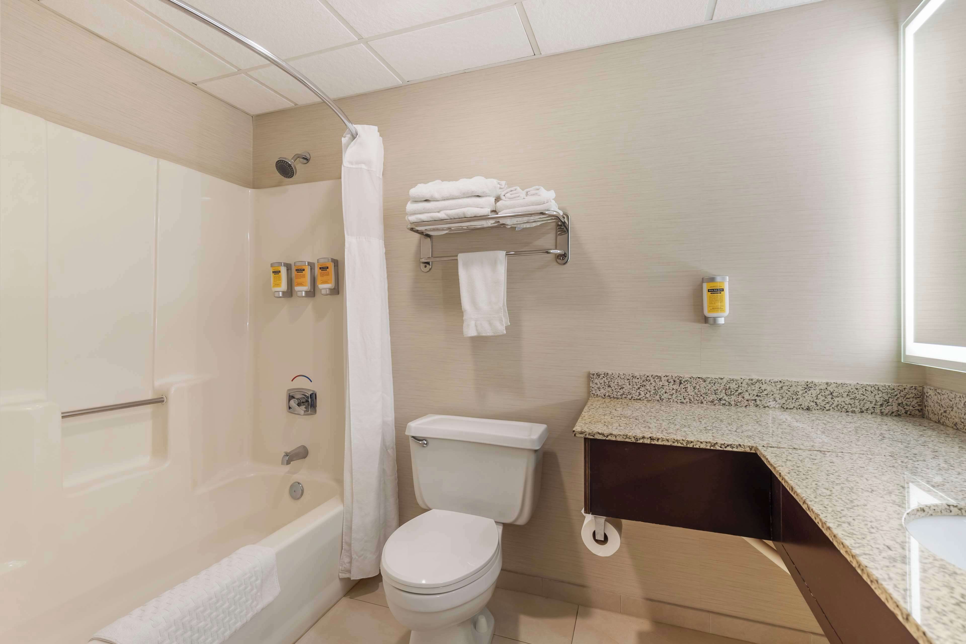 A bathroom with a bathtub, toilet, and a towel rack with folded towels.