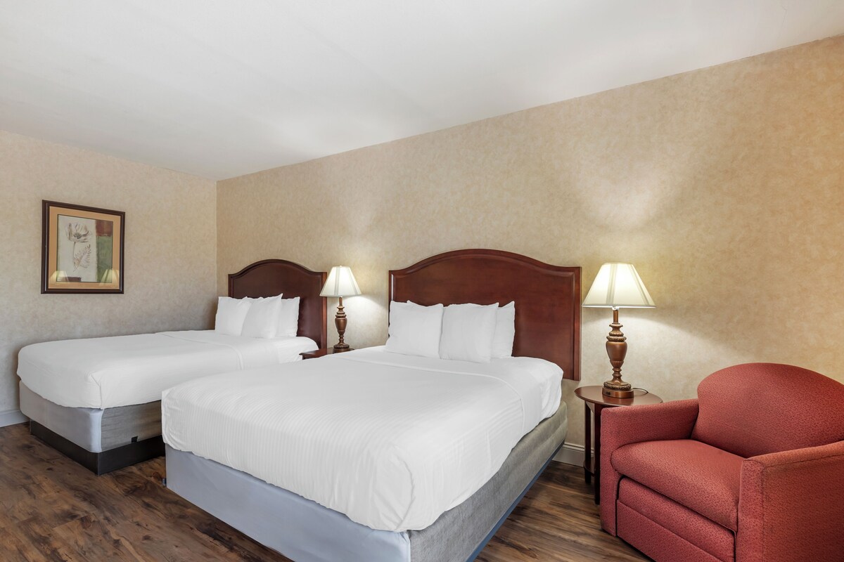 A hotel room with two single beds, a red armchair, and two bedside lamps.