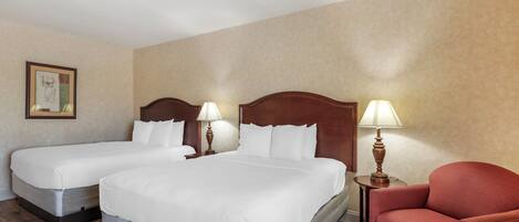 A hotel room with two single beds, a red armchair, and two bedside lamps.
