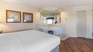 A bedroom with a bed, a bathroom with a sink and mirror, and a door.
