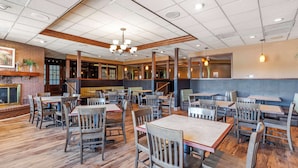 A spacious restaurant with wooden tables and chairs, a brick accent wall, and a chandelier.