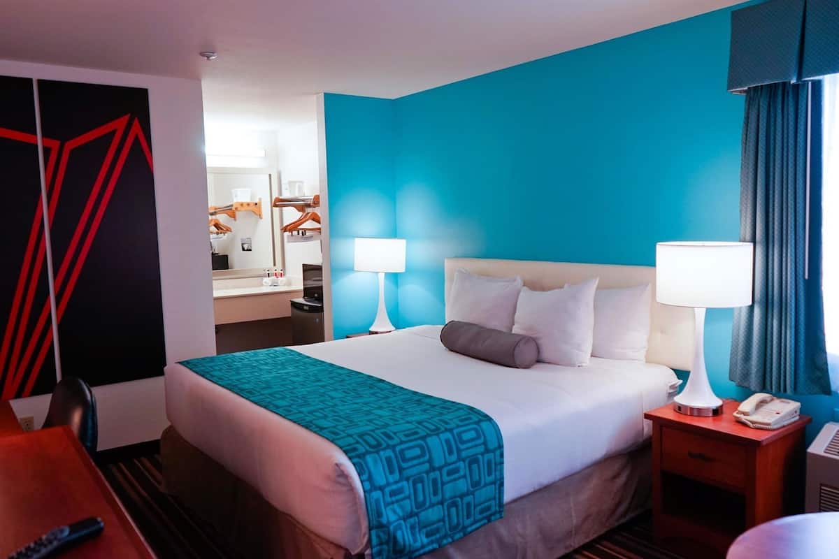 A hotel room with a bed, two bedside tables, a desk, and a chair.