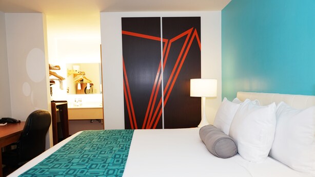 A hotel room with a bed, a desk, a chair, a wardrobe, and a mirror. - Howard Johnson by Wyndham Salinas (Salinas)