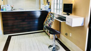 A reception area with a dark wood reception desk, a white counter, a computer, and a magazine rack. - Howard Johnson by Wyndham Salinas (Salinas)
