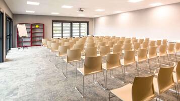 A conference room with rows of chairs, a whiteboard, and a projector on the ceiling.