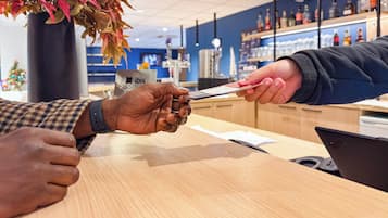 A person holding a card at a counter in a store with shelves of products in the background.
