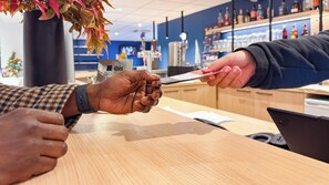 A person holding a card at a counter in a store with shelves of products in the background.