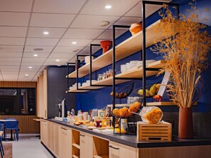 Una cocina moderna con estantes de madera, un mostrador central con alimentos y un jarrón decorativo con plantas secas.