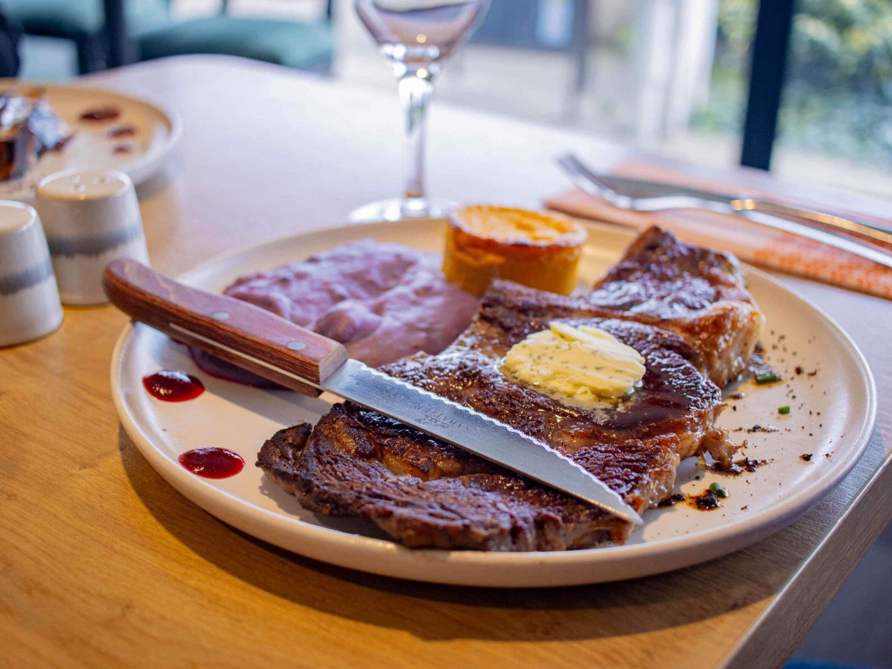 A plate with steak, butter, and a side of beans.
