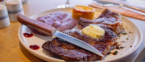 A plate with steak, butter, and a side of beans.