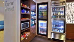 A corner market with shelves stocked with snacks, a microwave, and a refrigerator with beverages. - Fairfield Inn By Marriott Ann Arbor (Ann Arbor)