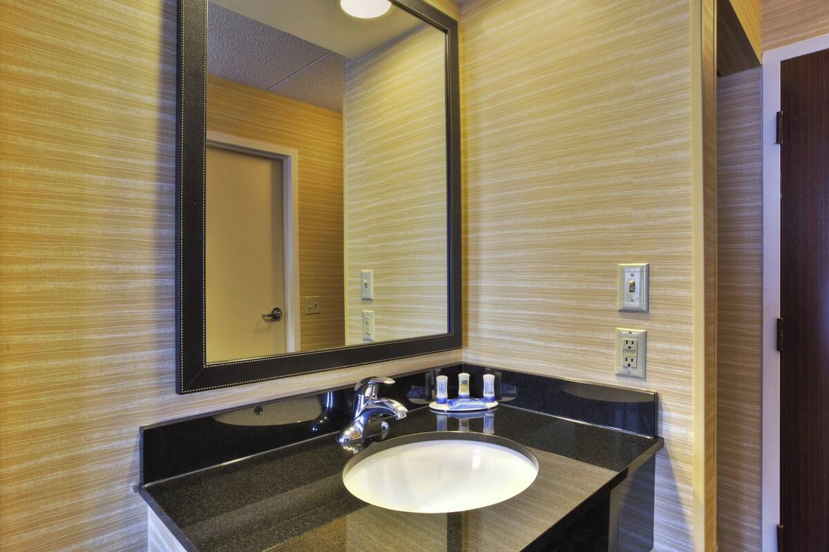 A bathroom with a large mirror, a sink, and a door.
