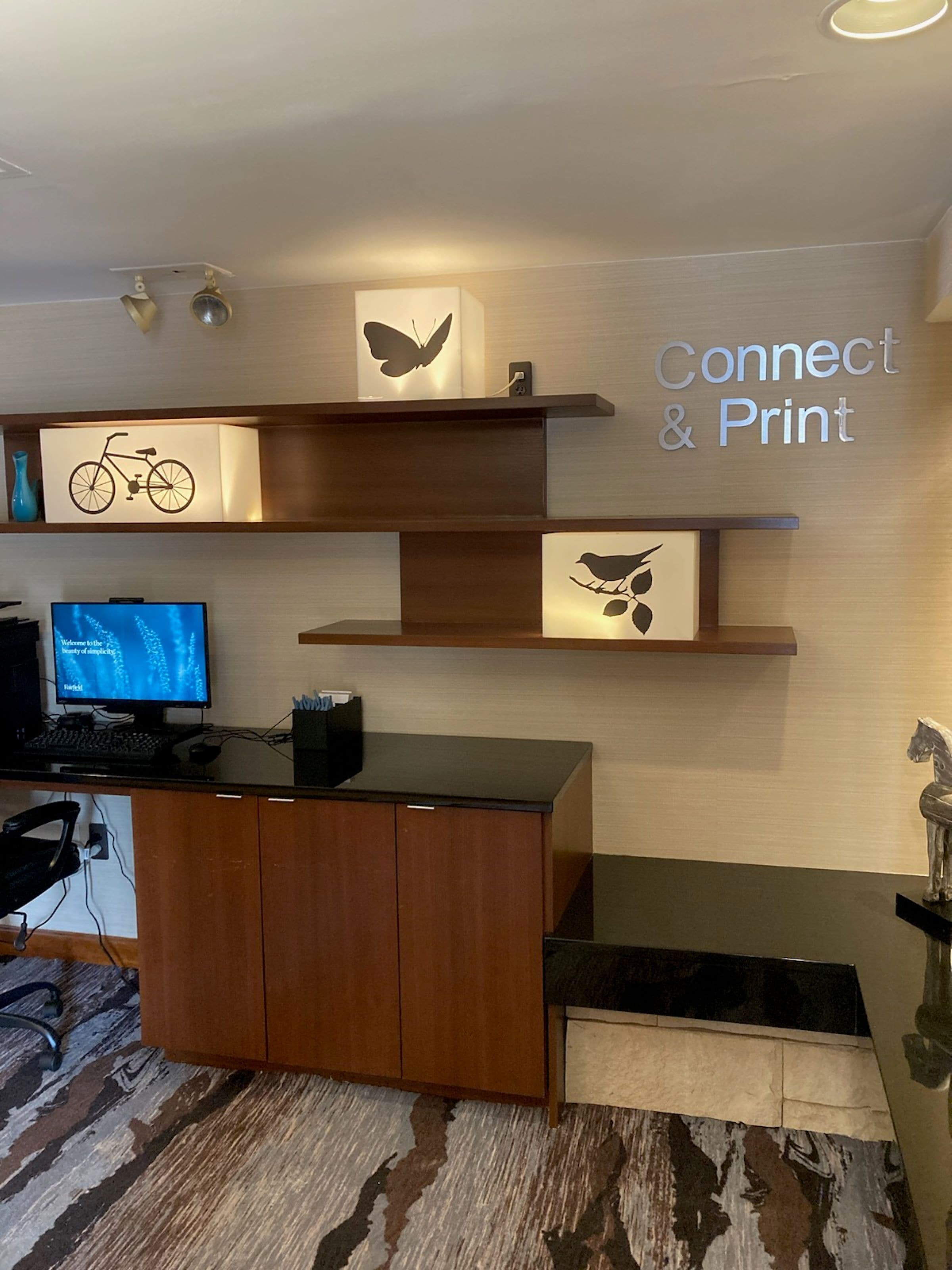 A reception area with a wooden desk, a computer monitor, and a sign that reads "Connect & Print".