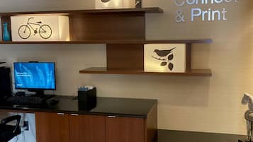 A reception area with a wooden desk, a computer monitor, and a sign that reads "Connect & Print".