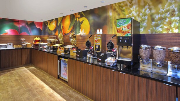 A buffet counter with various food items and a coffee machine. - Fairfield Inn By Marriott Ann Arbor (Ann Arbor)