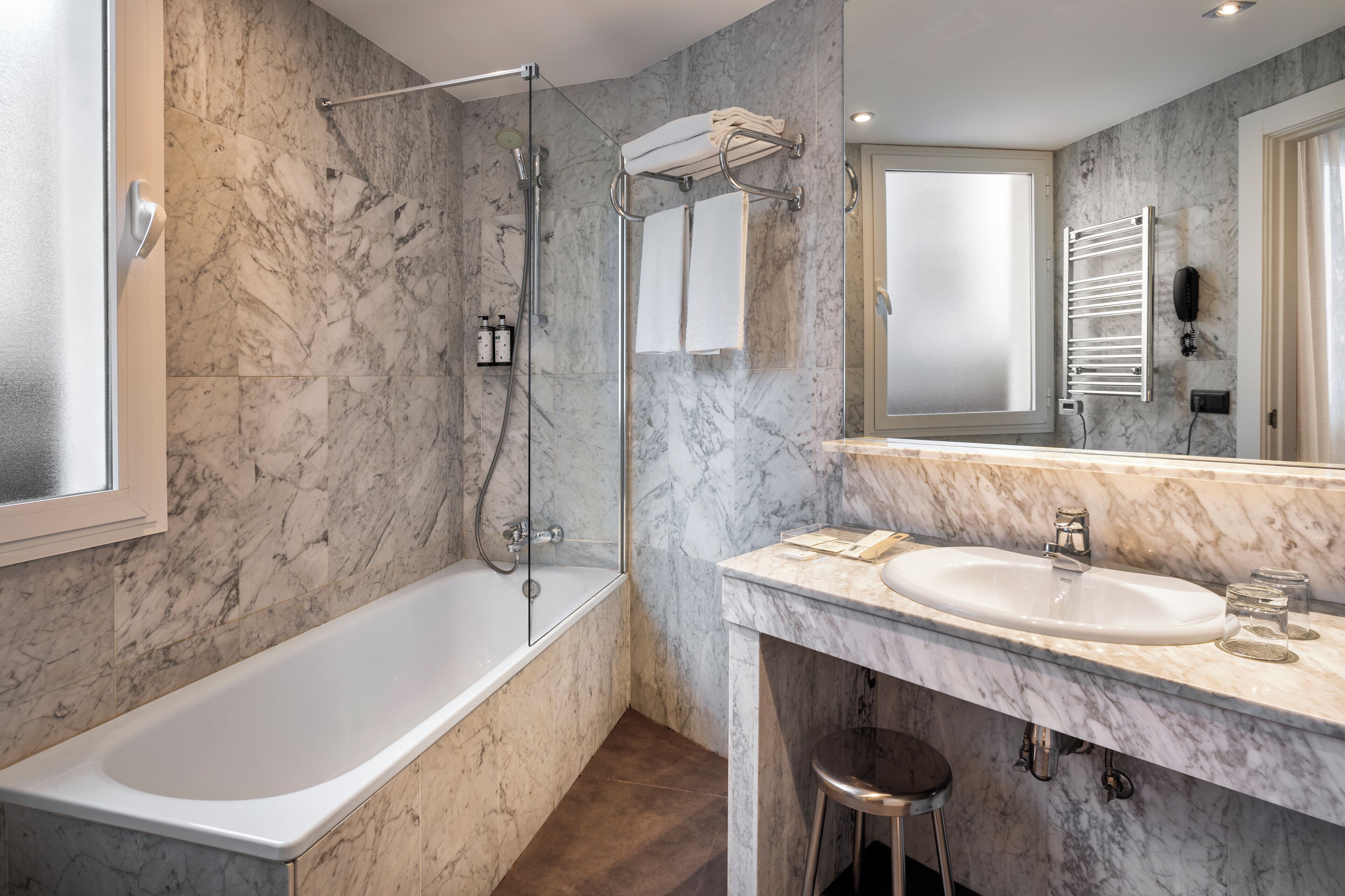 A modern bathroom with a marble floor, a bathtub, a shower, a sink, and a mirror.