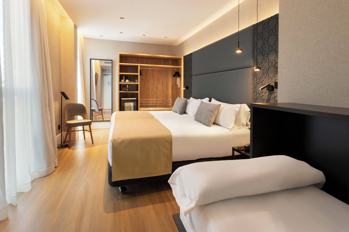 A modern hotel room with two beds, a walk-in closet, and a large mirror.