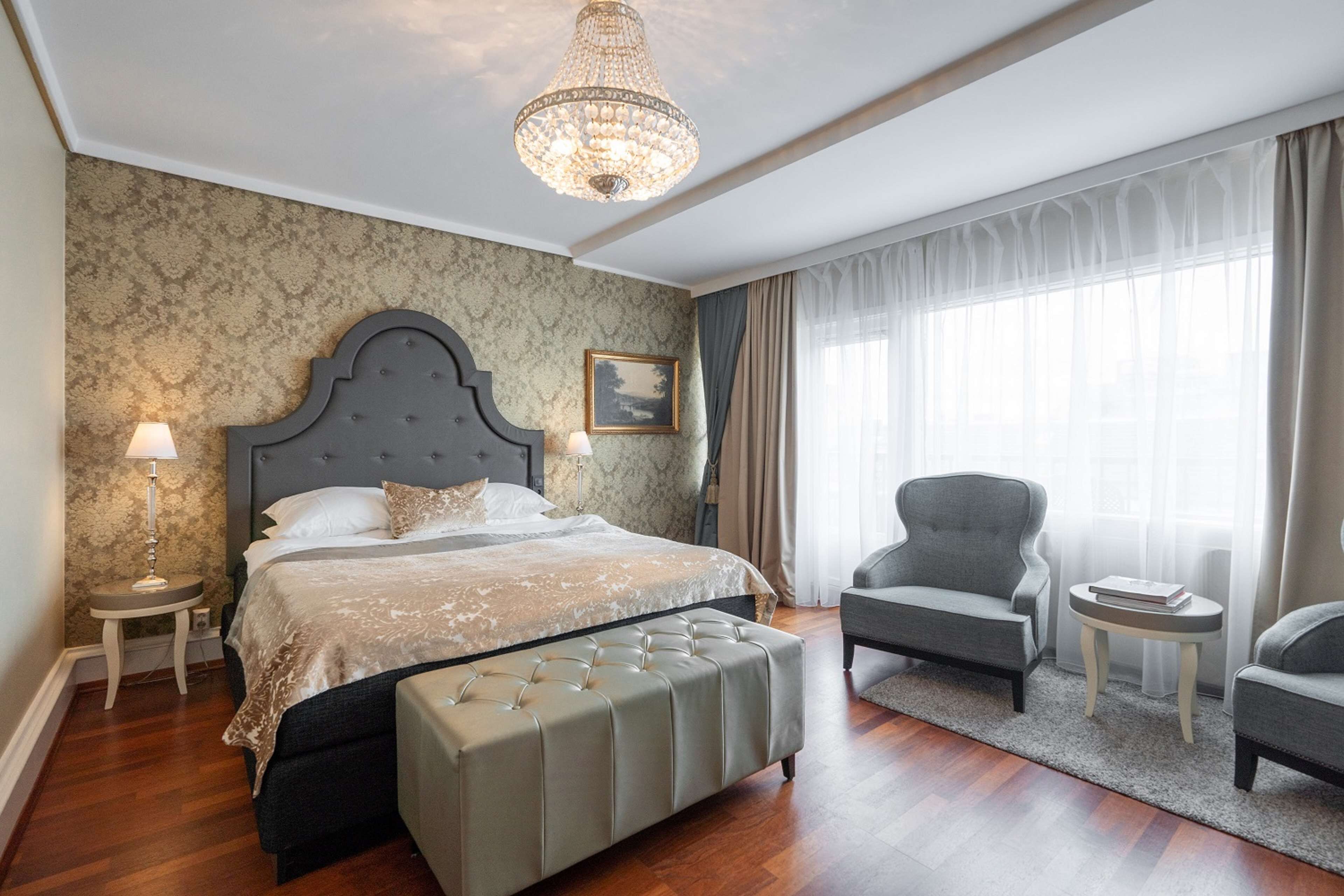 Une chambre à coucher avec un grand lit, un lustre, une chaise et une petite table.