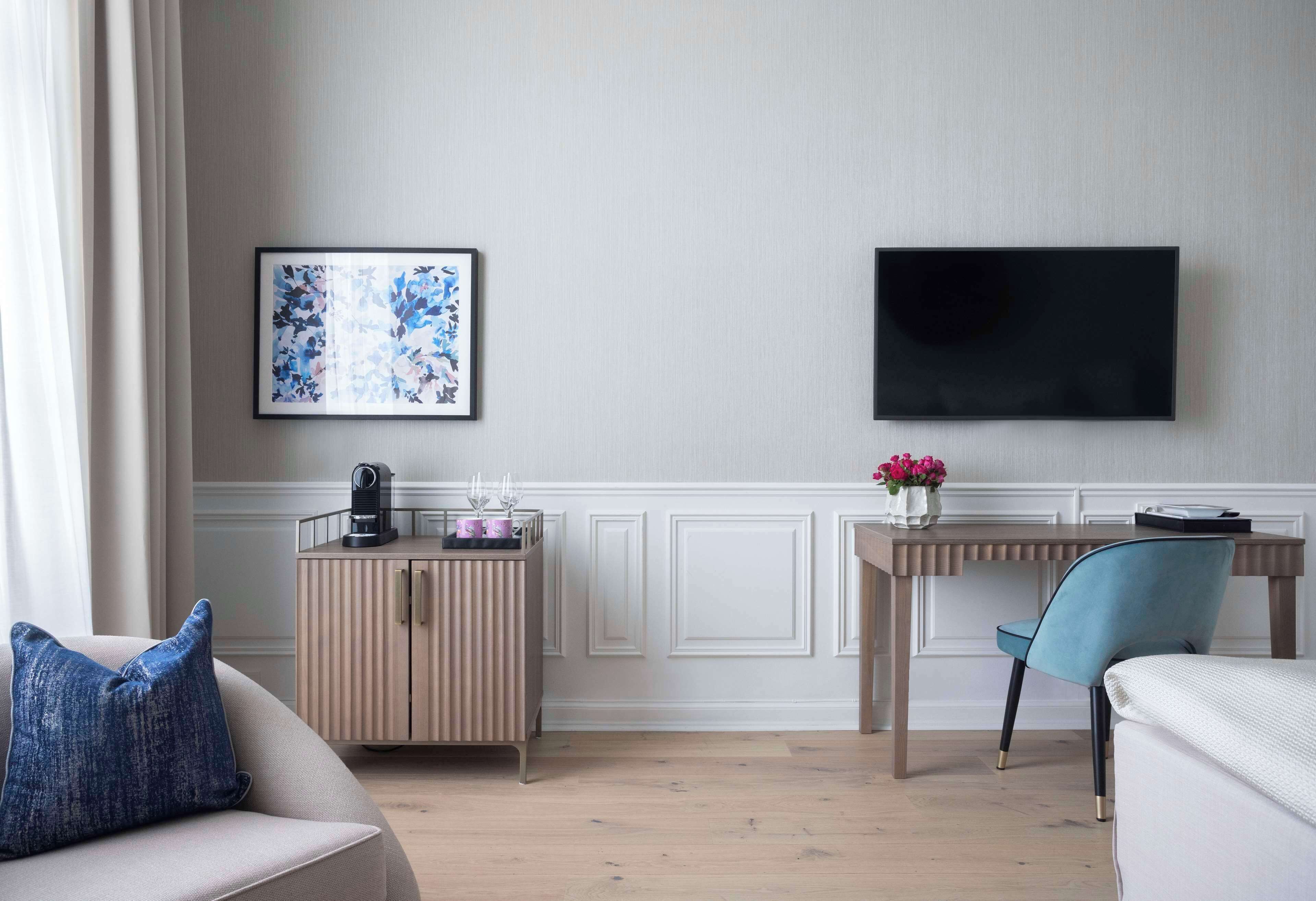 Una sala moderna con sofá, una mesa de centro, televisor montado en la pared y un mueble de madera.