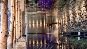 A modern interior with a reflective floor, vertical wooden columns, and a textured wall.
