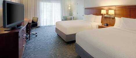 A hotel room with two beds, a TV, a desk, and a chair.