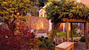 A garden patio with a pergola, stone wall, and outdoor seating area. - Hampton Inn Wheeling (Wheeling)
