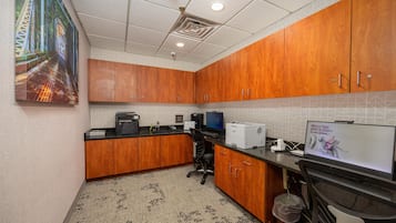 A kitchen with wooden cabinets, a computer, and a printer.